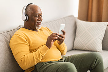 Man sitting on couch listening to music on his mobile phone
