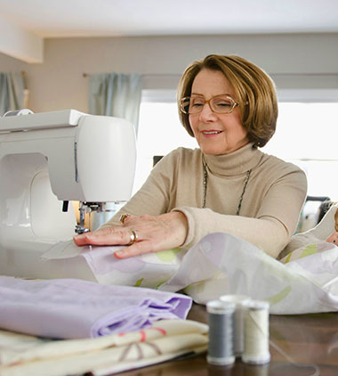 Woman smiles while using a sewing machine