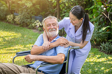 Caregiver with resident in a wheelchair outdoors at a assisted care facility