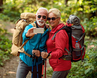 Retired couple taking selfing while backpacking