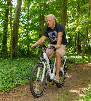 Retired man riding bike along a tree-lined path