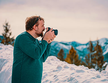 Photographer taking photo in snow covered wilderness