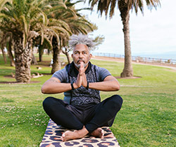 man doing yoga in park near ocean